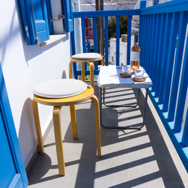 One of the balconies of Vento Aureo with a small tables, two stools and a bottle of wine
